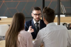 Serious broker giving advise to young couple.